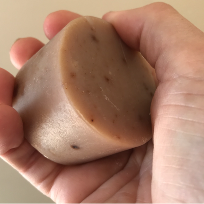 round eczema soap for face and body held in hand to show 100gm size