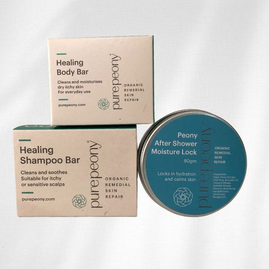 Boxed Healing Body Bar ontop of Boxed Shampoo Bar next to 80gm tin of Peony After Shower Moisture Lock makes up the bundle called Dry Skin Rescue Trio